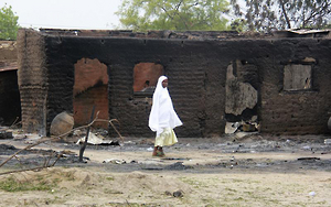 A WOMAN WALKS PAST BURNED HOUSES IN THE REMOTE TOWN OF BAGA, NORTHERN NIGERIA, ON APRIL 21, 2013. © 2013 Reuters 