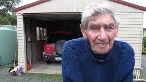 Bob Edwards at his home in New Zealand, his red Mitsubishi parked in his garage