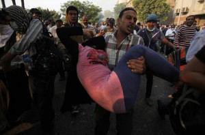 A member of the Muslim Brotherhood and supporter of ousted Egyptian President Mohamed Mursi carries a woman after riot police released tear gas at Kornish El Nile