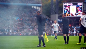 A referee steps onto the field after getting hit by a smoke bomb thrown after Tottenham scored a goal during the English Premier League football match at Villa Park in Birmingham on Oct. 20, 2013.