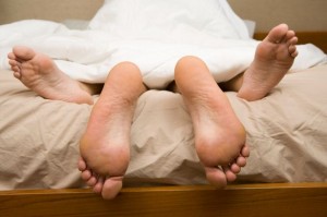 View of feet of couple having sex in bed-1384637