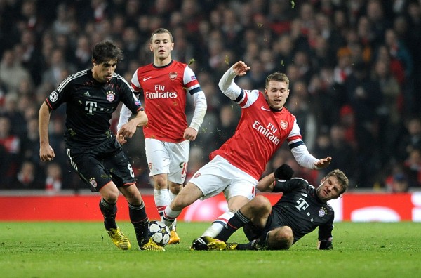 Thomas Muller Tackles Arsenal's Lukas Podolski in a Round of 16 Tie at the Emirate Stadium.Getty Image.