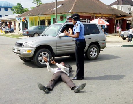 MR SUNDAY OMOTAYO BEING PLEADED WITH BY A POLICE OFFICER ON GOVT. HOUSE RD., UYO. (CREDIT: NAN)