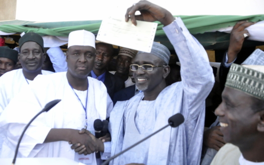 EDUCATION MINISTER, IBRAHIM SHEKARAU RAISING THE 2MILLION CHEQUE DONATED TOWARDS THE PRESIDENT’S RE-ELECTION BY THE YOUTH