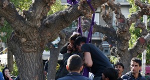 People rush to cut down two Pakistani migrants who tried to commit suicide by hanging themselves with twisted lengths of fabric from a tree in central Athens' Victoria Square on Thursday, Feb. 25, 2016. Bystanders said the men were upset because of delays in their planned travel to northern Greece, from which migrants start their long trek through the Balkans to wealthier European countries. The men, one of whom was unconscious, were rushed to hospital. Victoria Square is where most newly-landed migrants head after reaching Athens from the Aegean Sea islands. (AP Photo/Thanassis Kamvyssis)